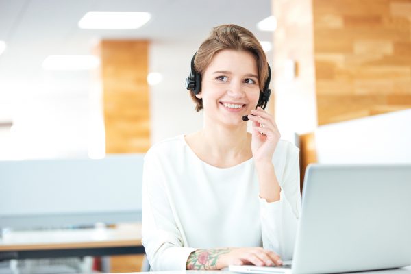 Cheerful attractive young woman sitting and working in call center