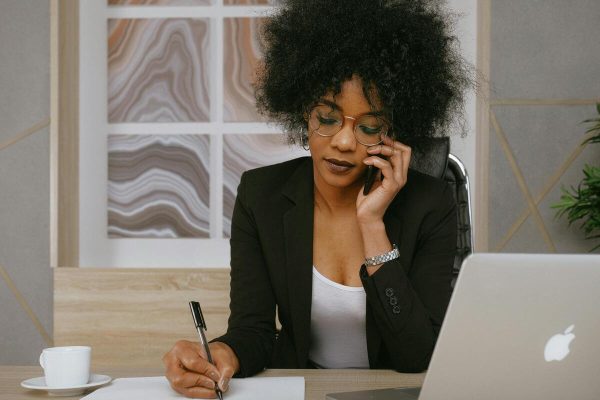 Woman taking customer service calls and notes, demonstrating fast response time customer service