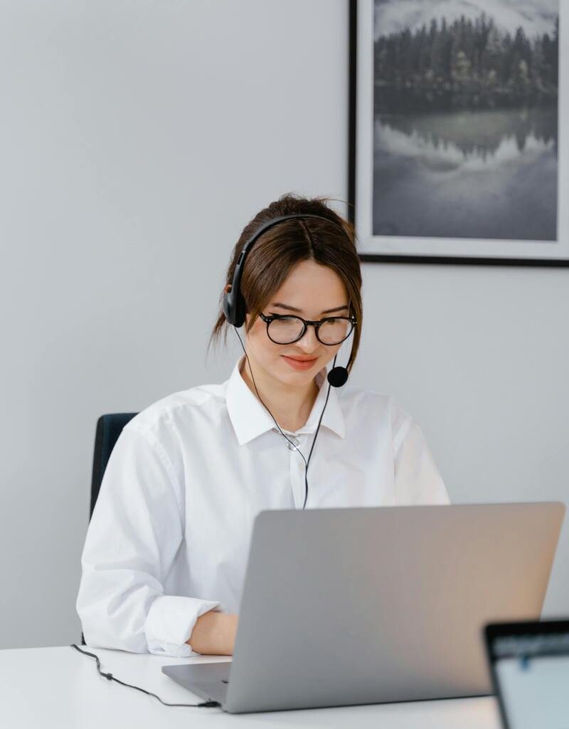 Customer service agent wearing a headset while providing software help desk outsourcing support using a laptop in a modern office