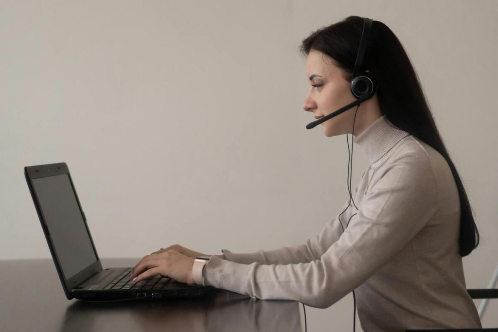 Technical support outsourcing agent answering customer calls with taking help from laptop