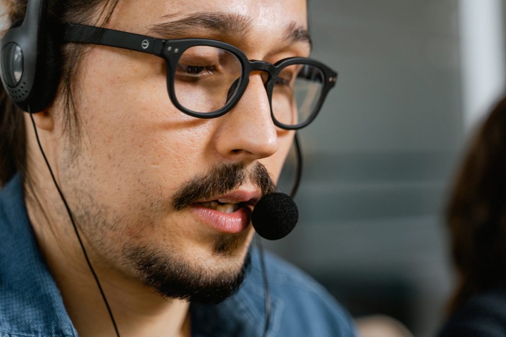 Back office support call center agent assisting customers wearing headset and glasses