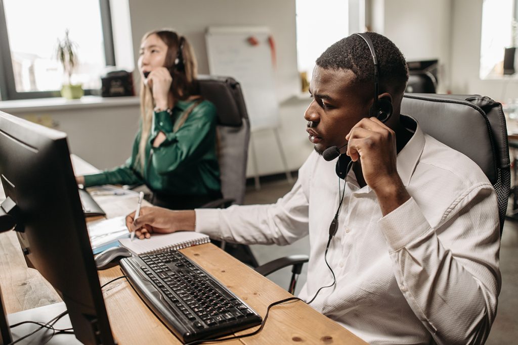 Remote customer support teams assisting customers over phone calls while taking notes