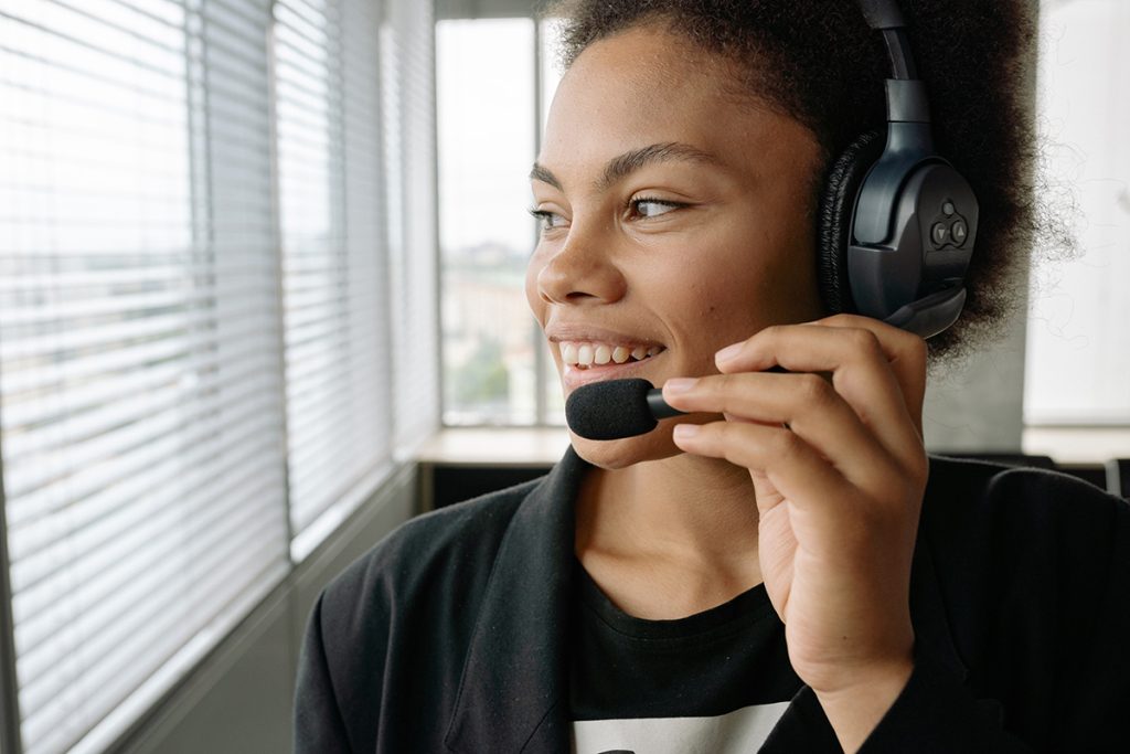 Dedicated customer support agent handling customer calls with a friendly smile in a professional office.
